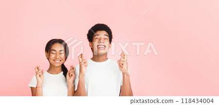 Hope for good luck. Cheerful african-american students cross fingers and smiling, pink background 118434004
