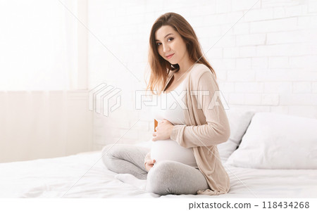 Happy pregnant woman touching her belly, anticipating future motherhood, empty space 118434268