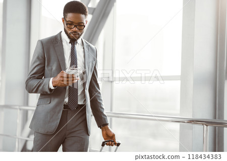 Businessman Texting on Smartphone Walking in Airport Terminal, Free Space Businessman Texting on Smartphone Walking in Airport Terminal, Free Space 118434383