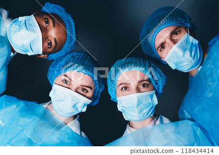 Team of Professional Surgeons Looking At Patient With Difficult Case Lying On Operating Table, Patient Pov Team of Professional Surgeons Looking At Patient With Difficult Case Lying On Operating Table, Patient Pov 118434414