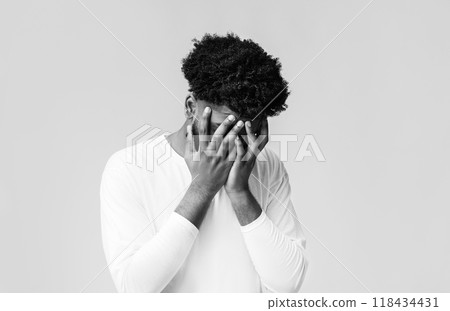 Young black man covering face with two hands, disappointed or stressed, orange studio background, copy space Young black man covering face with two hands, disappointed or stressed, orange studio background, copy space 118434431
