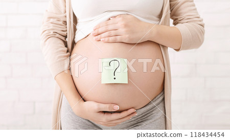 A pregnant woman standing and showing her belly with a question mark drawn on it, symbolizing uncertainty or curiosity during pregnancy, cropped A pregnant woman standing and showing her belly with a question mark drawn on it, symbolizing uncertainty or curiosity during pregnancy, cropped 118434454