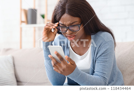 Can not believe my eyes. Sceptical afro woman in eyeglasses reading unexpected message on smartphone, full of disbelieve or having vision problem Can not believe my eyes. Sceptical afro woman in eyeglasses reading unexpected message on smartphone, full of disbelieve or having vision problem 118434464