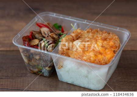 A box of  stir-fried duck with Thai basil, served over steamed rice and topped with a perfectly fried egg. 118434636