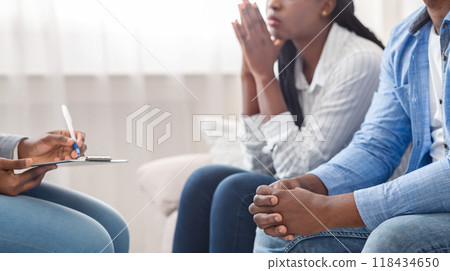 Marital psychotherapy. Unrecognizable african american couple sitting on couch at counselor's office, crop 118434650