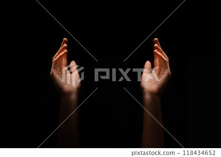 This image shows two hands reaching upward in the dark. The hands are positioned symmetrically, with their palms facing upwards. 118434652