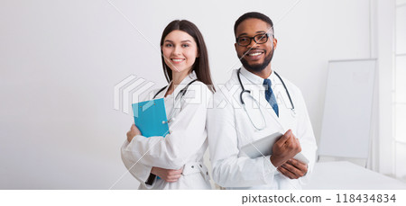 Two Doctors In White Coats Posing To Camera At Conference, Copy Space Two Doctors In White Coats Posing To Camera At Conference, Copy Space 118434834