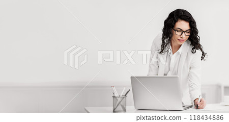 Note Taking. Happy mexican businesswoman in glasses at work, standing at desk and writing to do list, copyspace Note Taking. Happy mexican businesswoman in glasses at work, standing at desk and writing to do list, copyspace 118434886