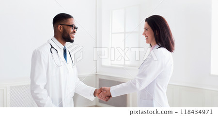 Doctor handshaking with african-american intern after meeting in clinic 118434971
