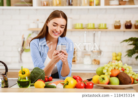 Young Woman Texting when Cooking Healthy Food In Kitchen, Copy Space 118435314