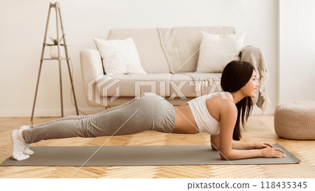 Home Training. Girl Doing Plank Exercise, Working Out in Living Room, Side View 118435345