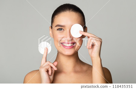 Skin Care. Girl Removing Makeup with Cotton Pads, Having Fun on Grey Background Skin Care. Girl Removing Makeup with Cotton Pads, Having Fun on Grey Background 118435351