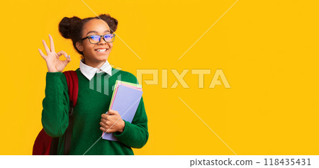 Everything Is Okay. Smiling black teenage girl showing ok sign, looking at camera over yellow wall, panorama, copyspace 118435431