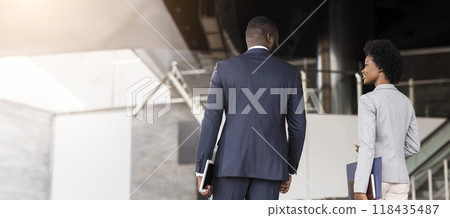 Happy african business partners leaving office building after successful meeting, side view Happy african business partners leaving office building after successful meeting, side view 118435487
