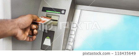 Close up of black man using ATM with gold credit card, panorama, copy space 118435649
