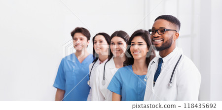 Team of doctors and interns standing in hospital in row and looking aside 118435692