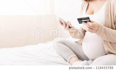 Mother shopping online for her baby, using smartphone and credit card in bed, empty space 118435789