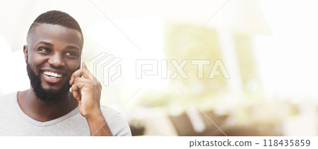 A man smiles while talking on his cell phone in a modern office setting. 118435859