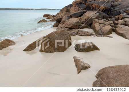 Rocky coastline at Gurteen Bay in Ireland with boulders on soft sand, clear shallow Atlantic waters 118435912