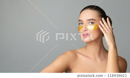 Beauty Woman with Eye Patches Showing Effect of Perfect Skin on Grey Studio Background Beauty Woman with Eye Patches Showing Effect of Perfect Skin on Grey Studio Background 118436021