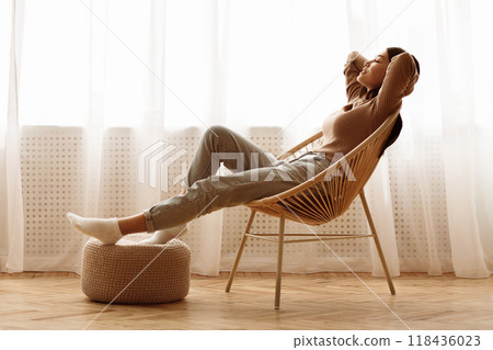Weekends Finally. Relaxed Girl Sitting on Modern Chair near Window, Enjoying Morning 118436023