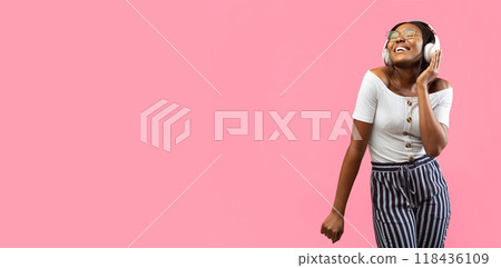 Happy Afro Woman In Wireless Headphones Listening To Music And Dancing On Yellow Background In Studio. Panorama, Empty Space Happy Afro Woman In Wireless Headphones Listening To Music And Dancing On Yellow Background In Studio. Panorama, Empty Space 118436109