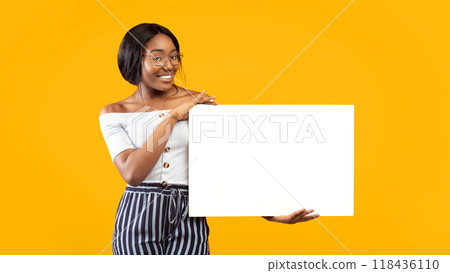 Millennial Afro Girl Holding Empty White Board Smiling At Camera Standing On Orange Studio Background. Mockup, Panorama Millennial Afro Girl Holding Empty White Board Smiling At Camera Standing On Orange Studio Background. Mockup, Panorama 118436110