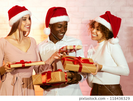 Merry Christmas. Two Girls In Santa Hats Giving Xmas Gifts And Presents To Friend Having Party Celebrating Winter Holidays At Home Merry Christmas. Two Girls In Santa Hats Giving Xmas Gifts And Presents To Friend Having Party Celebrating Winter Holidays At Home 118436329