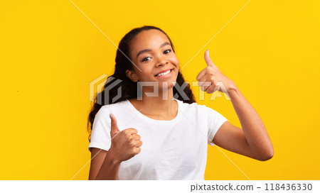 Great News. Smiling black teen girl showing thumbs up isolated on the yellow background. Free space Great News. Smiling black teen girl showing thumbs up isolated on the yellow background. Free space 118436330