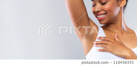 Close up of happy afro woman smelling her armpit over grey background Close up of happy afro woman smelling her armpit over grey background 118436355