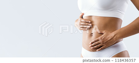 Close up of female beautiful body over grey background, afro woman touching her abdomen, slimming concept 118436357
