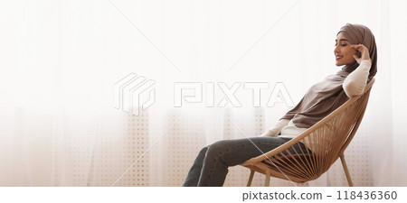 Enjoying Home Comfort. Portrait of young arabic woman relaxing in cozy wicker chair in light living room in apartment, side view with copy space Enjoying Home Comfort. Portrait of young arabic woman relaxing in cozy wicker chair in light living room in apartment, side view with copy space 118436360