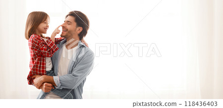 Adorable little girl touching her dad nose, playing together at home, free space 118436403