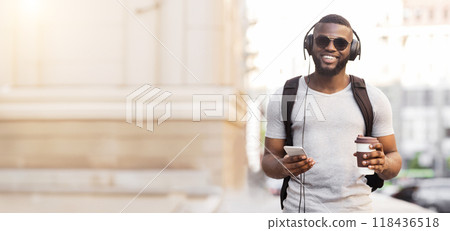 Handsome african american guy going to work with coffee and headphones in the morning, panorama, free space 118436518