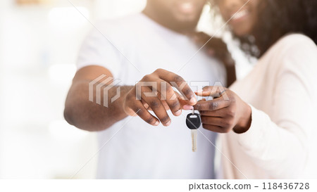 A couple is smiling and holding a set of car keys indoors. 118436728