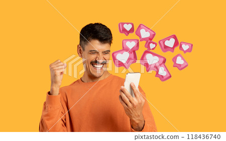 Isolated on orange, a millennial guy with moustache laughs and celebrates with his phone, got a love message from his girlfriend 118436740