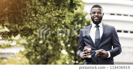 Portrait of cheerful african employee having coffee break and using smartphone outdoors, empty space 118436919