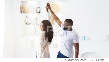 A couple dances in a white room, the man leading the woman with a smile. A couple dances in a white room, the man leading the woman with a smile. 118437045