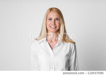 A smiling woman with blonde hair and wearing a white button-down shirt stands against a white background. Her bright white shirt has a collar and long sleeves A smiling woman with blonde hair and wearing a white button-down shirt stands against a white background. Her bright white shirt has a collar and long sleeves 118437090