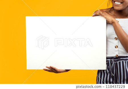 Unrecognizable Black Girl Holding Blank White Poster Standing On Orange Background. Studio Shot, Cropped, Mockup 118437229