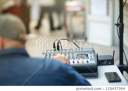 Audio Technician Adjusting Mixing Console at Live Event 118437364