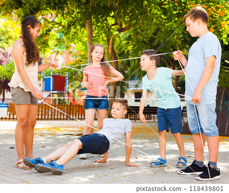 Interesting children's games. Boy carefully passes through a tangled rope Interesting children's games. Boy carefully passes through a tangled rope 118439801