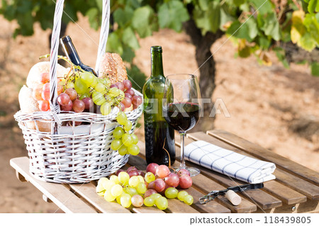 Still life with glass of red wine grapes and picnic basket on table Still life with glass of red wine grapes and picnic basket on table 118439805