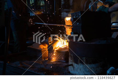 Pouring molten metal into a sand mold in the foundry shop of metallurgical plant 118439827