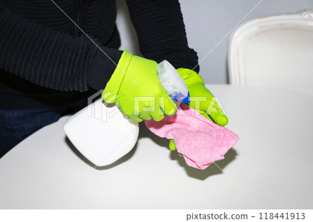 A man wearing cleaning gloves wipes the dining table. 118441913