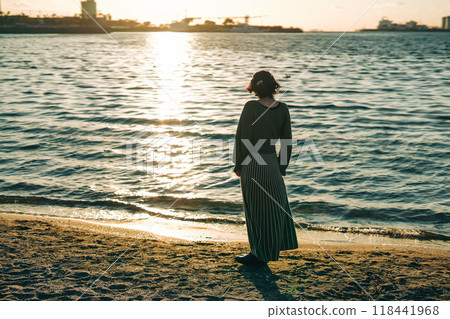 Woman walking by the sea watching the sunset Woman walking by the sea watching the sunset 118441968