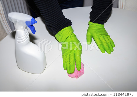 A man wearing cleaning gloves wipes the dining table. 118441973
