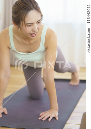 一位年輕女子在家參加線上瑜珈沙龍並擺姿勢 一位年輕女子在家參加線上瑜珈沙龍並擺姿勢 118442011