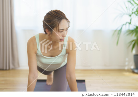 A young woman taking an online yoga class at home and posing A young woman taking an online yoga class at home and posing 118442014