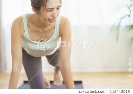 A young woman taking an online yoga class at home and posing A young woman taking an online yoga class at home and posing 118442016